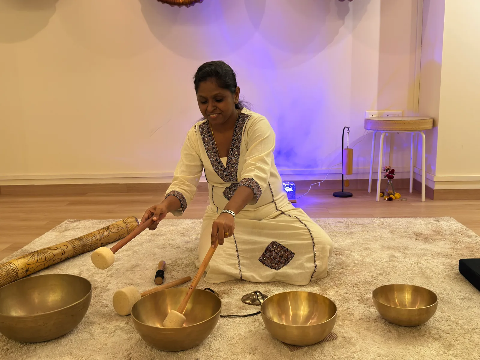 A smiling student playing two singing bowls at SAMA Studio, Pune